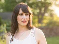 Burnout-syndrom - Frau in weißem Oberteil mit braunen Haaren, die besorgt guckt