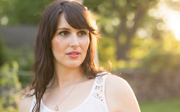 Burnout-syndrom - Frau in weißem Oberteil mit braunen Haaren, die besorgt guckt