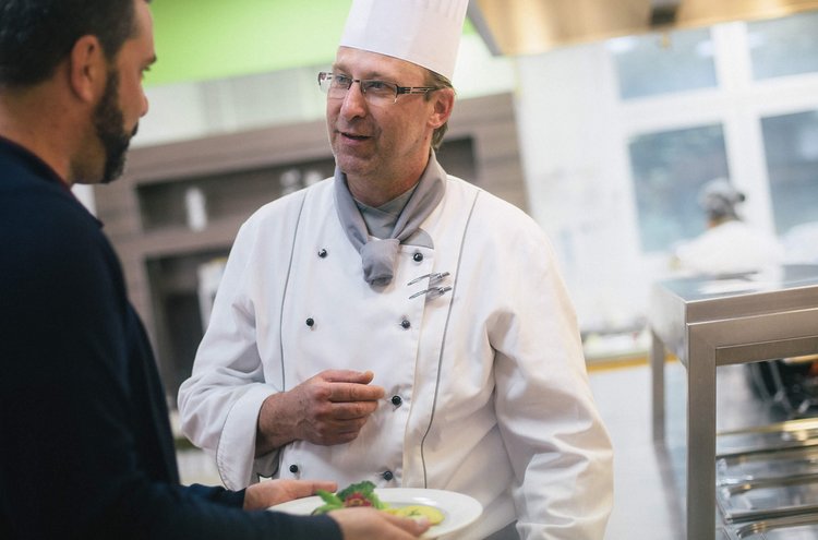 Mann unterhält sich mit Küchenchef und freut sich auf sein Essen.