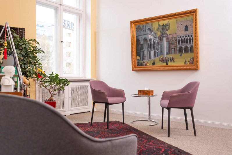 Ein freundlich gestalteter Therapieraum der Oberberg Tagesklinik Berlin mit zwei lila Sesseln, einem kleinen Tisch, Pflanzen und großem Gemälde an der Wand