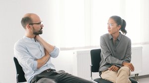 Ein Mann und eine Frau sitzen auf Stühlen und sprechen miteinander.