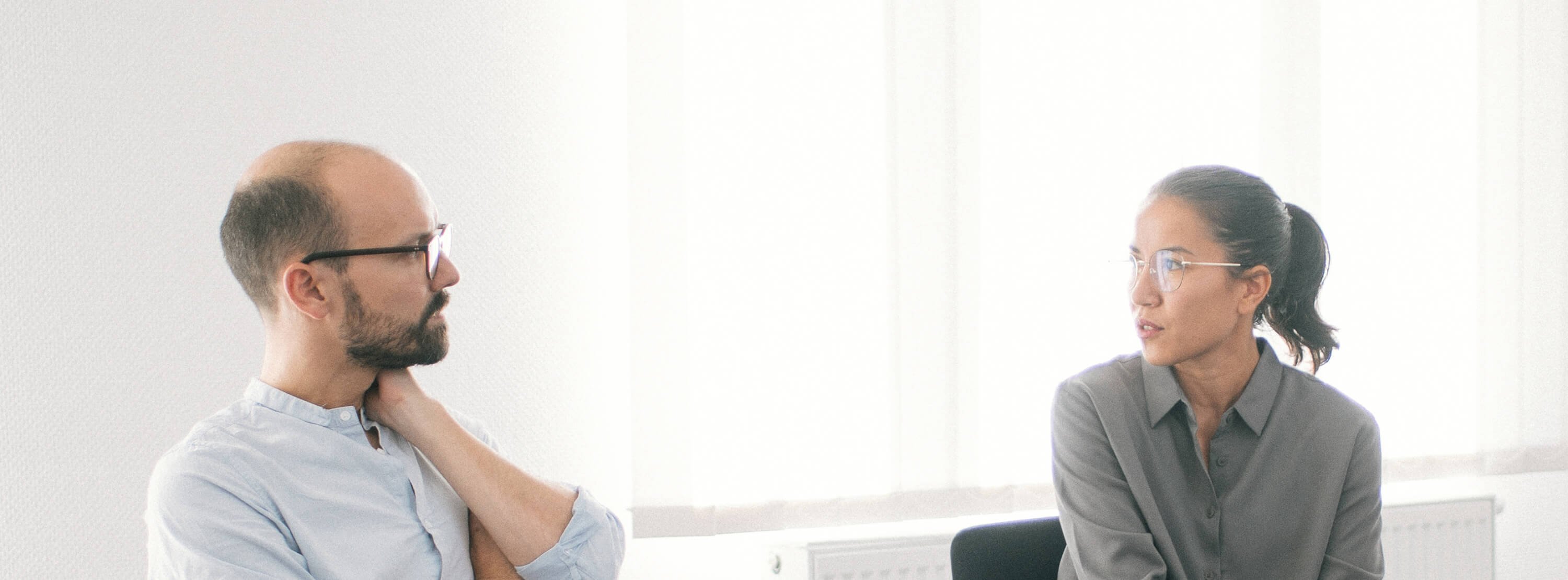 Ein Mann und eine Frau sitzen auf Stühlen und sprechen miteinander.