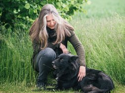 Artikel Borderline: Frau mit schwarzem Hund im Gras