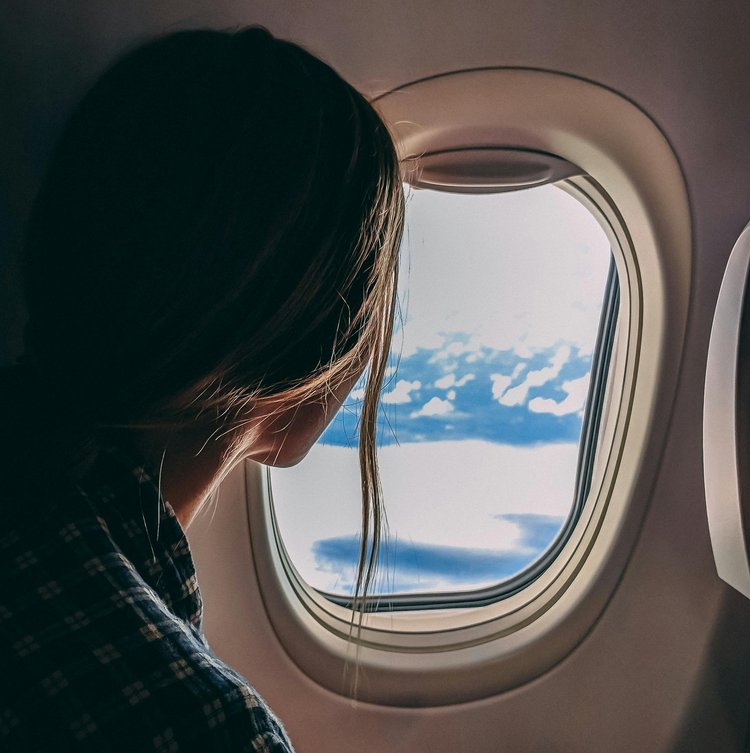 Frau sitzt im Flugzeug und schaut aus dem Fenster
