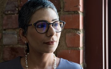 Artikel Psychische Krankheiten: Frau mit Brille vor einer Backsteinwand