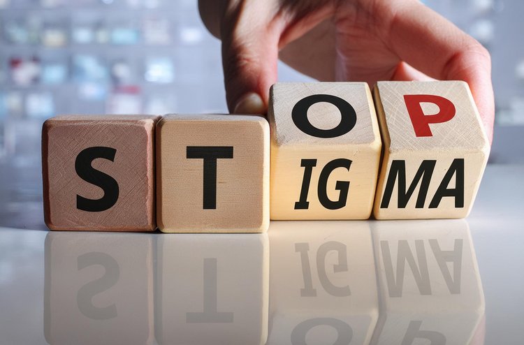 Hand dreht Holzwürfel auf denen STOP STIGMA stehen