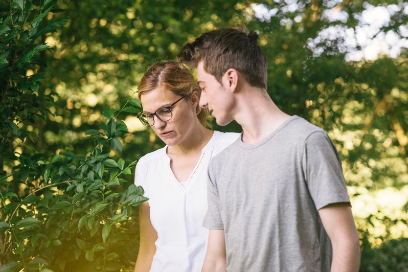 Therapiegespräch zur Behandlung Somatoformer Störungen (wie Chronische Schmerzen) zwischen Therapeutin und Patient mit Bäumen im Hintergrund