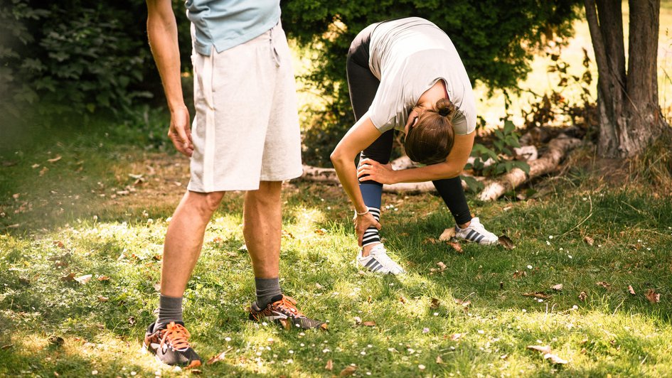 Mann und Frau im Wald machen Dehnübungen