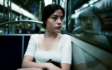 Frau sitzt im Bus und schaut aus dem Fenster, düstere Atmosphäre