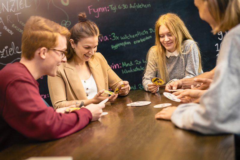 Patienten sitzen zusammen am tisch und spielen Karten