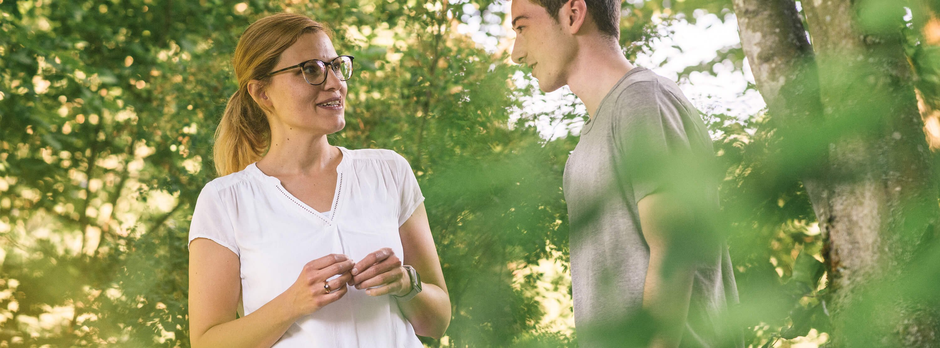 Therapeutin spricht während eines Waldspazierganges mit jungem Patienten.
