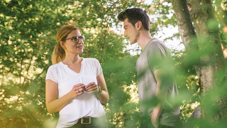 Therapeutin spricht während eines Waldspazierganges mit jungem Patienten.