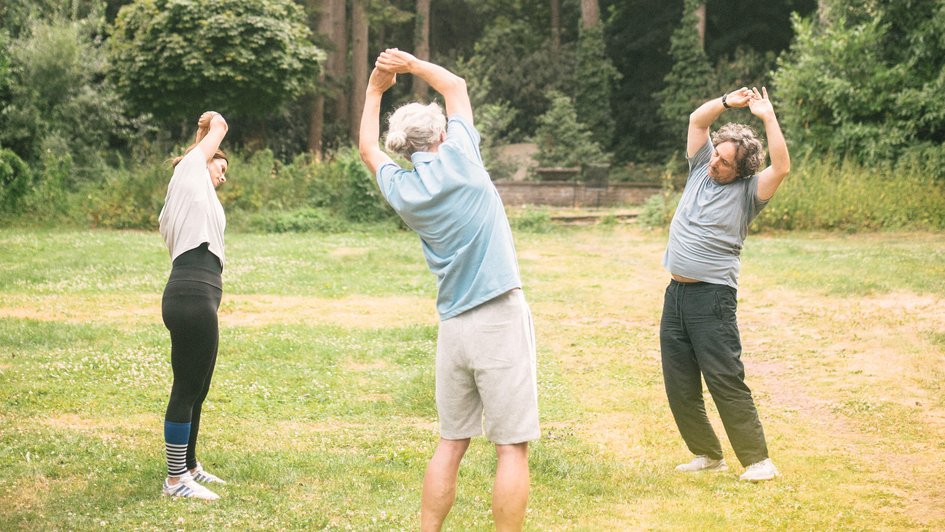 Gruppe von Menschen machen Dehnübungen im Wald