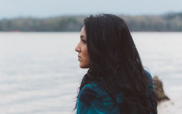 Borderline - Frau mit schwarzen Haaren, die aufs Wasser guckt