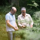 Eine Mann und eine Frau ertasten Blätter eines Strauchs.