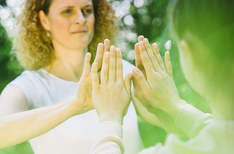 Theapeutin und Patientin stehen sich gegenüber und klatschen sich ab