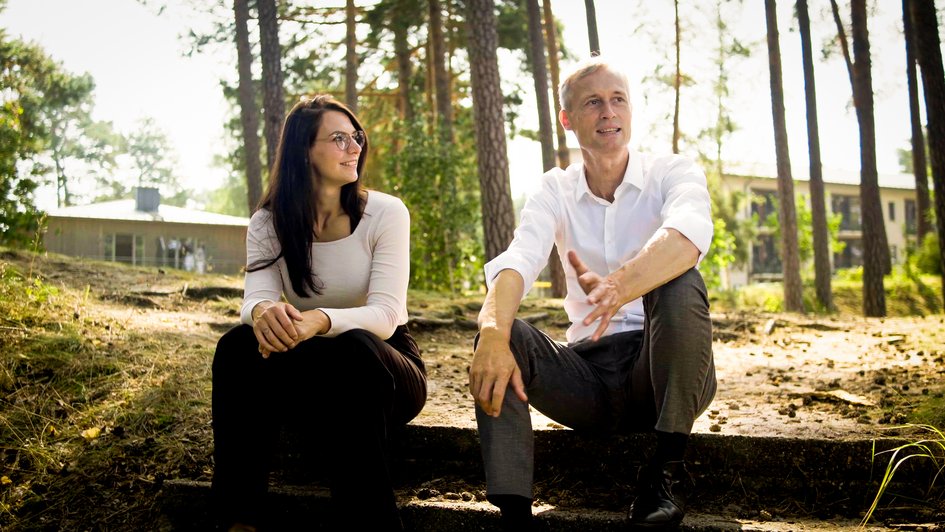 2 Personen sitzen gemeinsam im Grünen und unterhalten sich