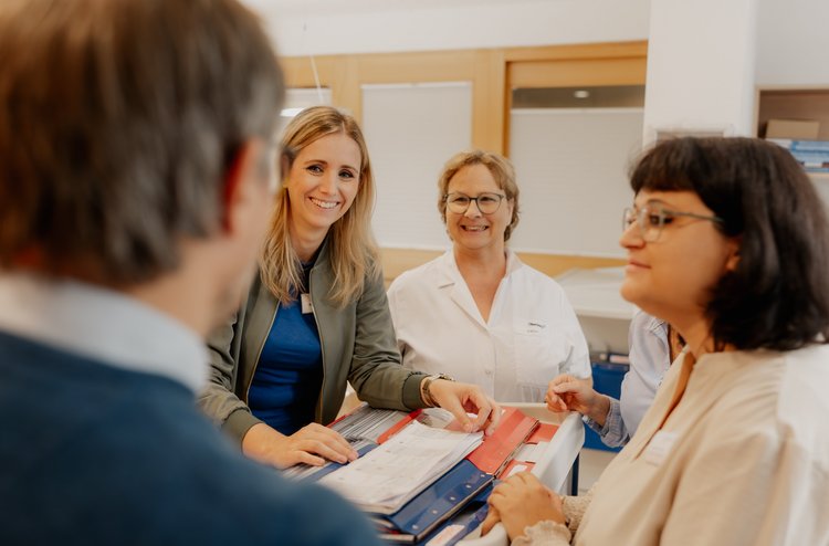 mehrere Mitarbeiter stehen um einer Kiste mit Akten und unterhalten sich