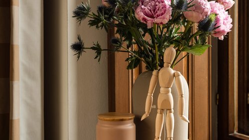 Holzpuppe vor einer Blume