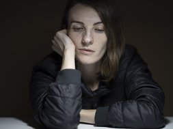 Frau in grauem Oberteil guckt traurig