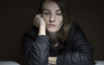 Frau in grauem Oberteil guckt traurig