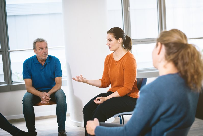 mehrere Personen sitzen im Kreis und unterhalten sich