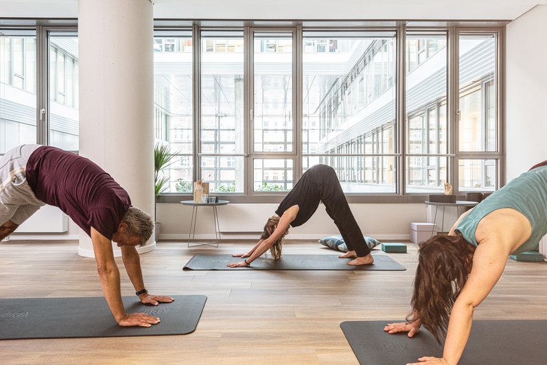 mehrere Personen in einem großen Raum, Yoga Position einnehmend