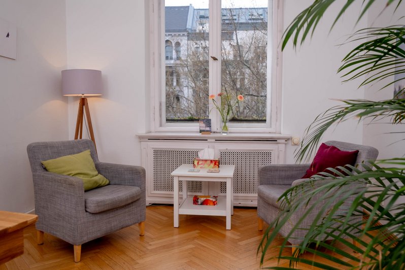 gemütliche kleine Ecke mit 2 grauen Sesseln und kleinem weißen Tisch unter einem Fenster