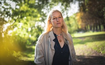 frau spaziert durch Park, besorgter Blick