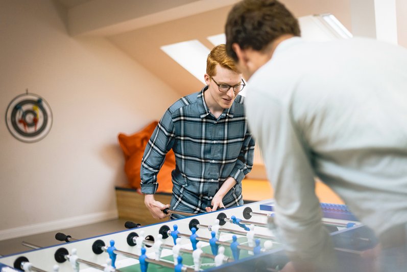 Zwei Personen spielen gegeneinander am Kickertisch