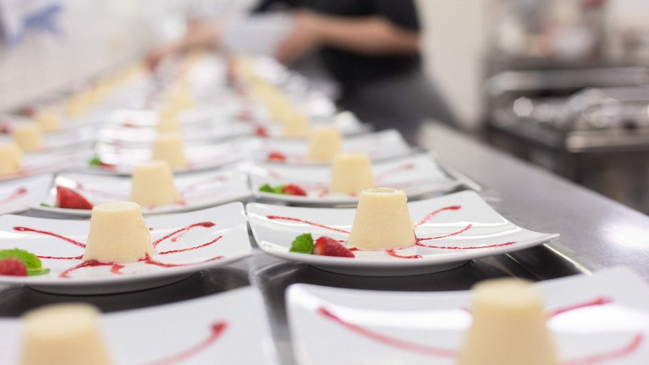 Eine Reihe von Tellern mit dekorierten Pudding-Törtchen 