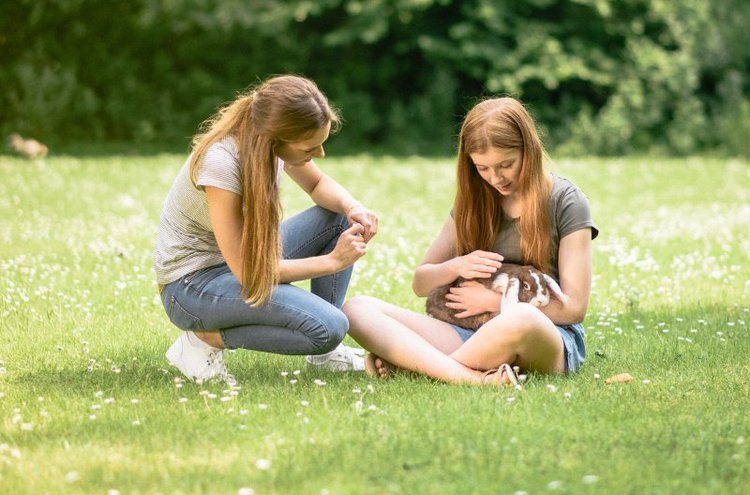 Zwei Mädchen auf einer Wiese mit einem Hasen
