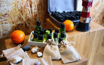 Aromatherapie Verschiedene Fläschchen, Orangen, Beutel und ein kleiner Leuchtturm