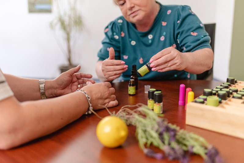 wei Personen bei der Anwendung ätherischer Öle mit verschiedenen Duftfläschchen und Lavendel auf einem Tisch