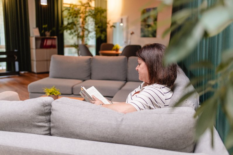 Frau sitzt auf großem Sofa und liest ein Buch