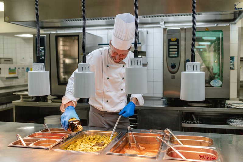 Chefkoch verfeinert das Mittagessen mit Olivenöl