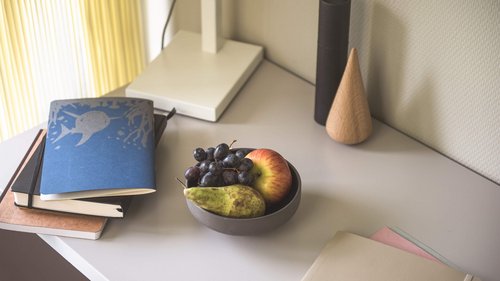 Schale mit Obst und Hefte auf einem Tisch