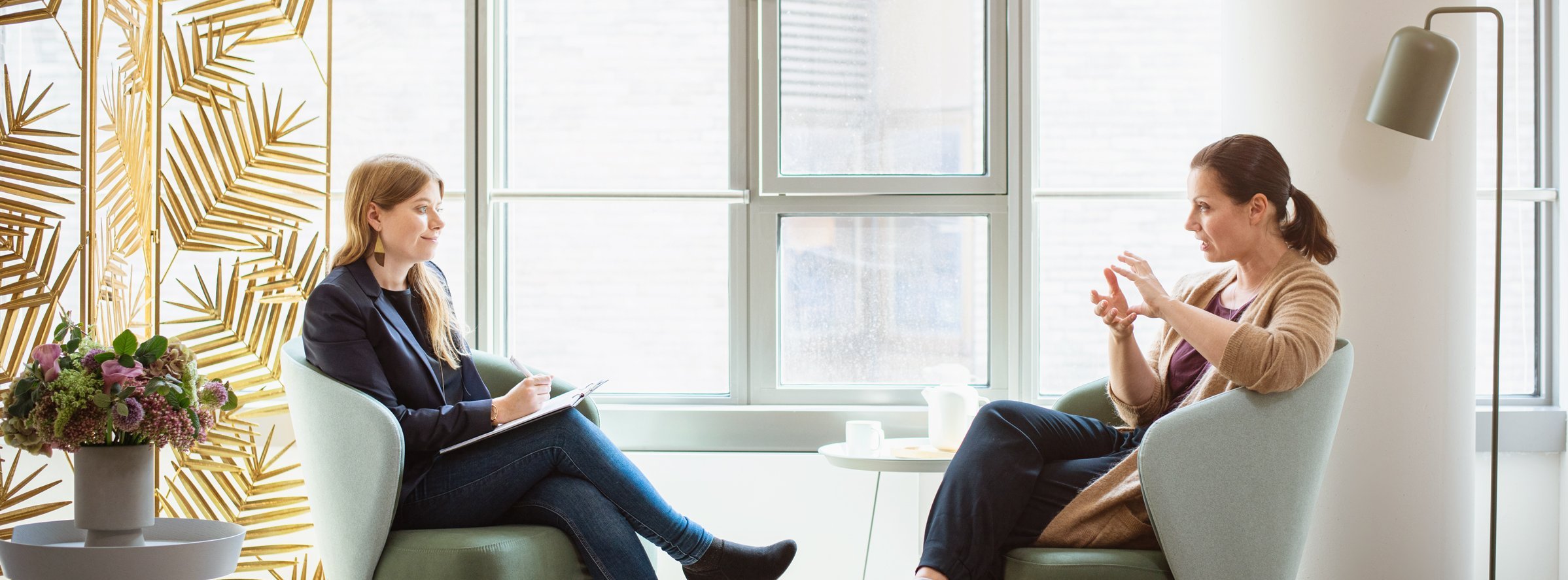 Zwei Frauen sitzen sich in hellgrünen Sesseln gegenüber und unterhalten sich