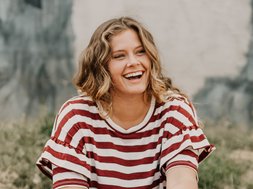 Depression - Eine junge lächelnde Frau in einem rot-weißen Oberteil