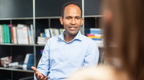 Therapeut vor einem Bücherregal