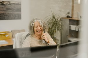 freunliche Mitarbeiterin sitzt am Schreibtisch und telefoniert