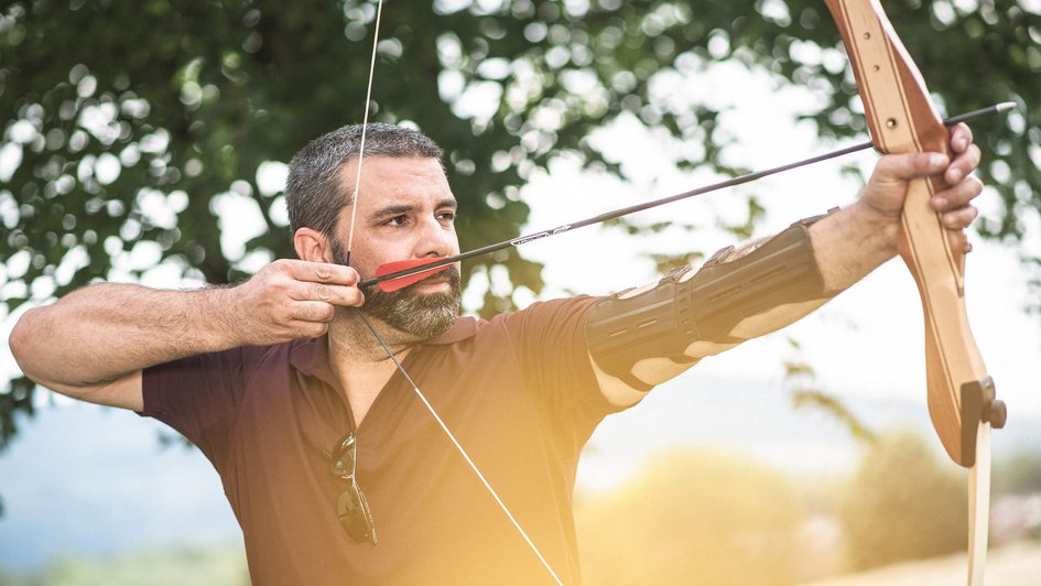 Blick auf sanfte Hügellandschaft in der Ferne in den Morgenstunden. Im Vordergrund eine Lichtung mit Waldbestand.