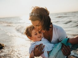 Depression - Mutter mit Kind an einem Strand