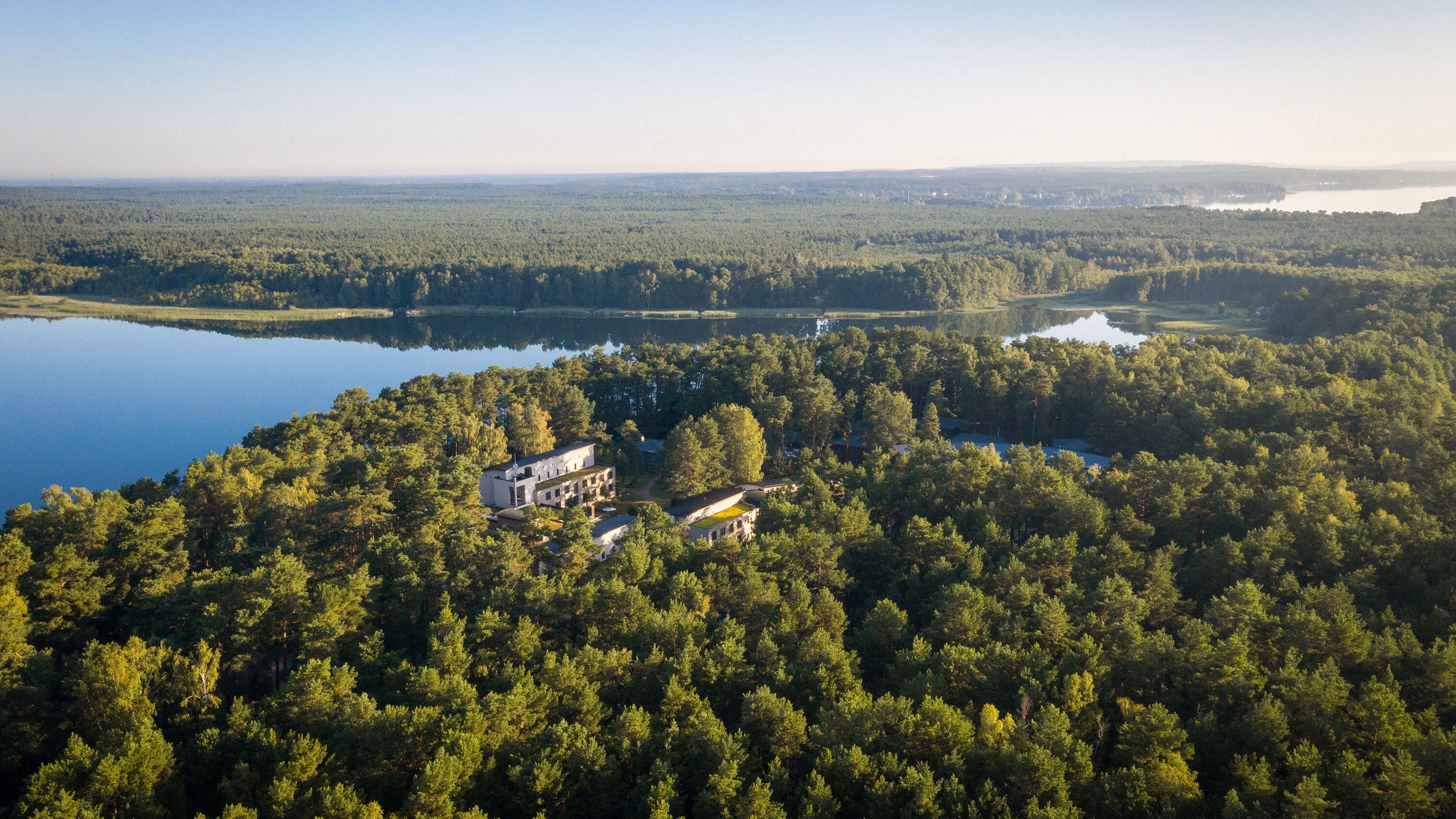 Panoramaaufnahme der Oberberg Fachklinik Berlin Brandenburg aus der Vogelperspektive. Großes Waldgebiet mit großem See.