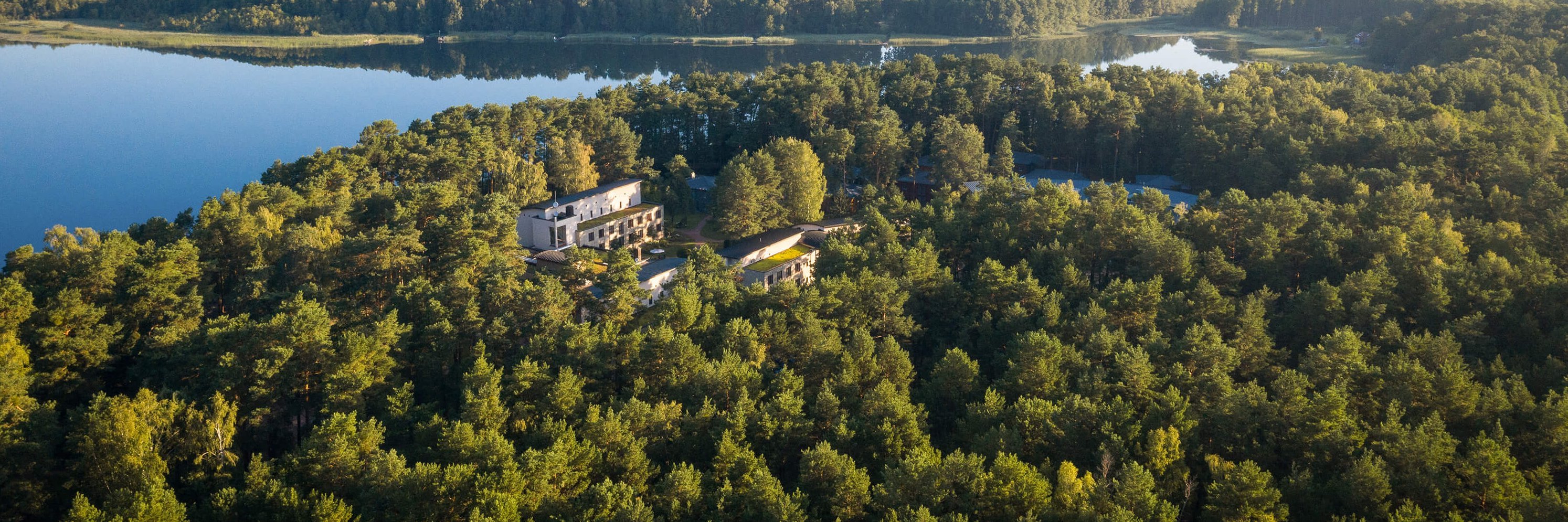 Panoramaaufnahme der Oberberg Fachklinik Berlin Brandenburg aus der Vogelperspektive. Großes Waldgebiet mit großem See.