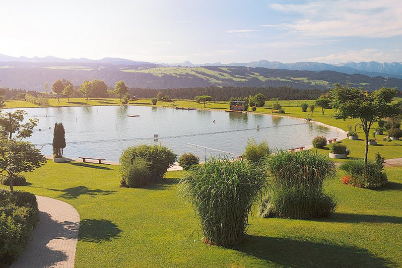 Naturbad umgeben von grünen Wiesen, Wäldern und Bergen