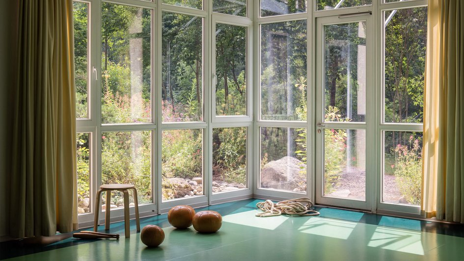 Sporthalle mit Medizinbällen und Seilen mit Ausblick in den Wald