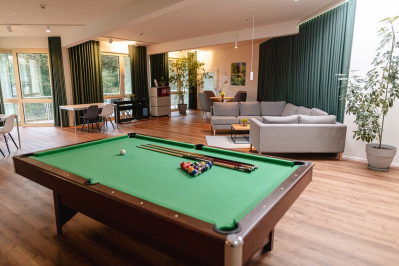 Aufenthaltsbereich mit Sitzmöglichkeiten und Billardtisch im Vordergrund