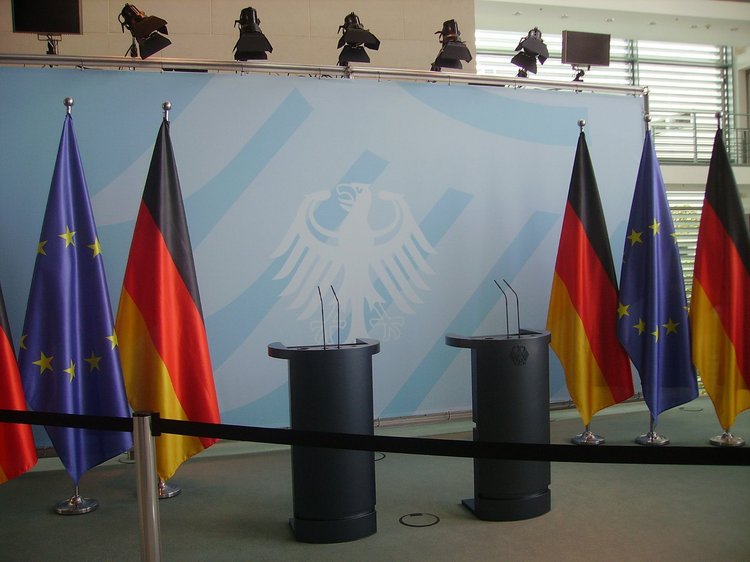 Artikel Folgen Covid-19, Leeres Podium mit Deutschland Flagge und EU Flagge