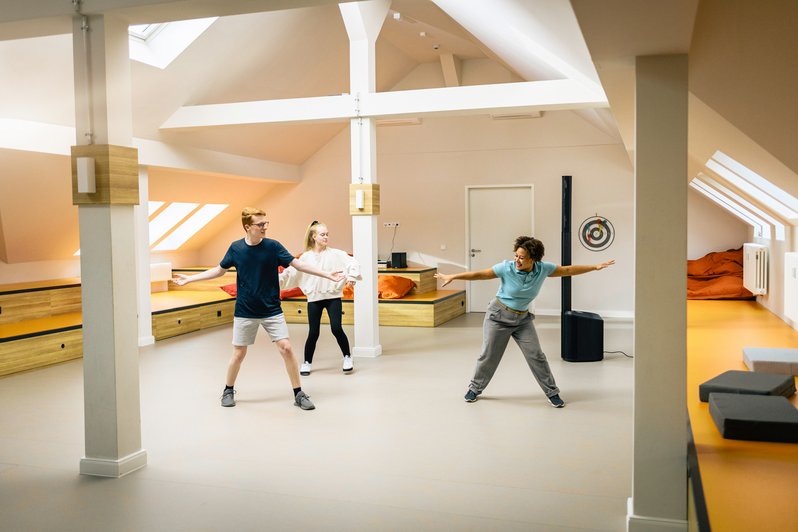 großer Sportraum unter dem Dach, Patienten mit Therapeutin in Bewegung